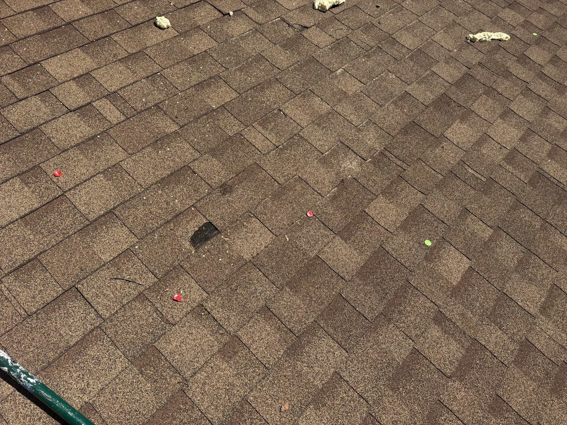 High-angle view of completed roof replacement showing uniform shingle alignment, proper flashing installation around chimney, and seamless integration with existing eaves and guttering system on residential home exterior.