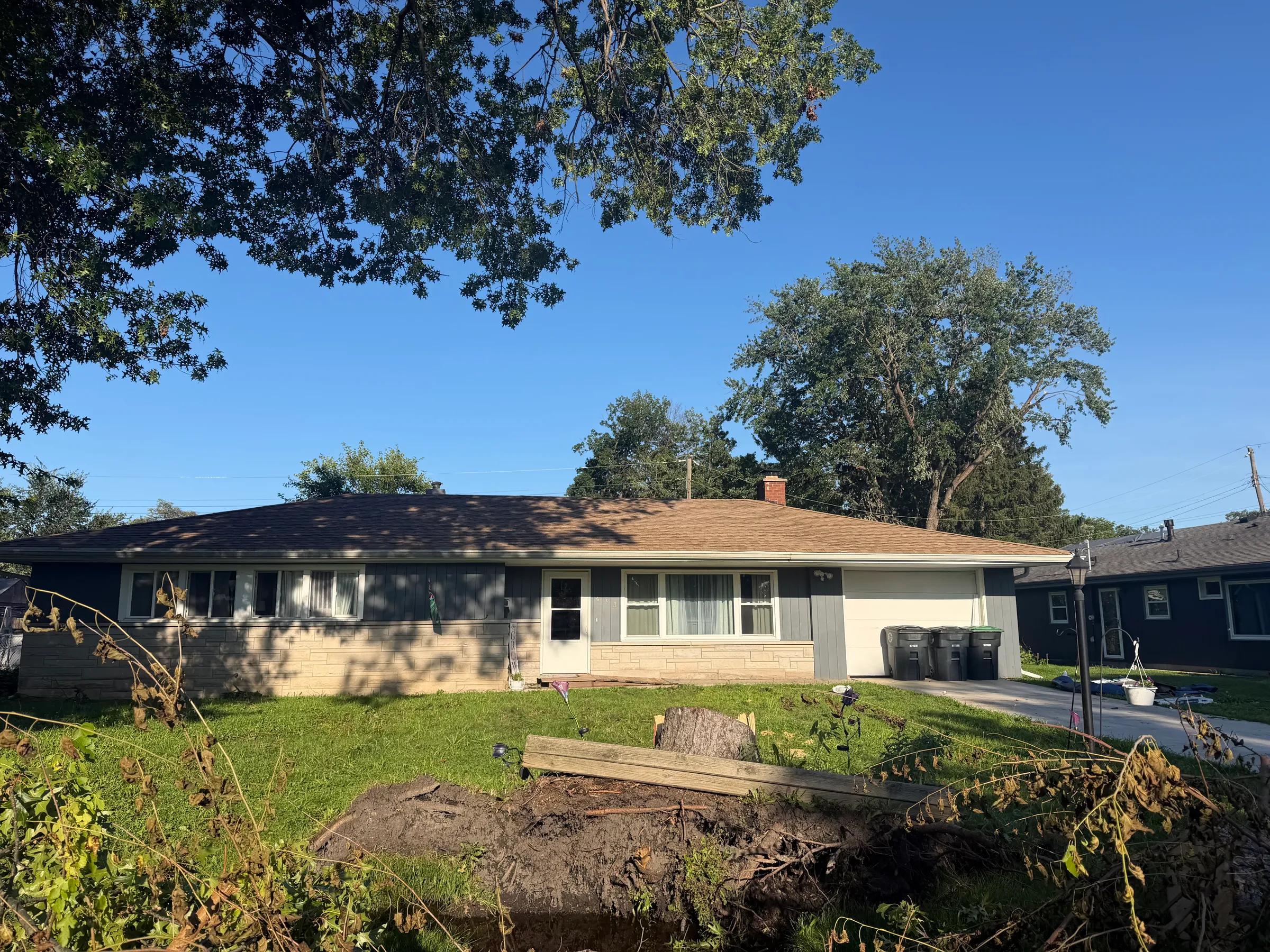 Three-quarter view of home exterior showing completed roof and siding work with proper color coordination, aligned shingles and siding courses, new flashing installation, and integrated gutter system.